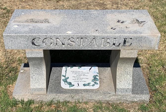 A granite memorial bench has stains.